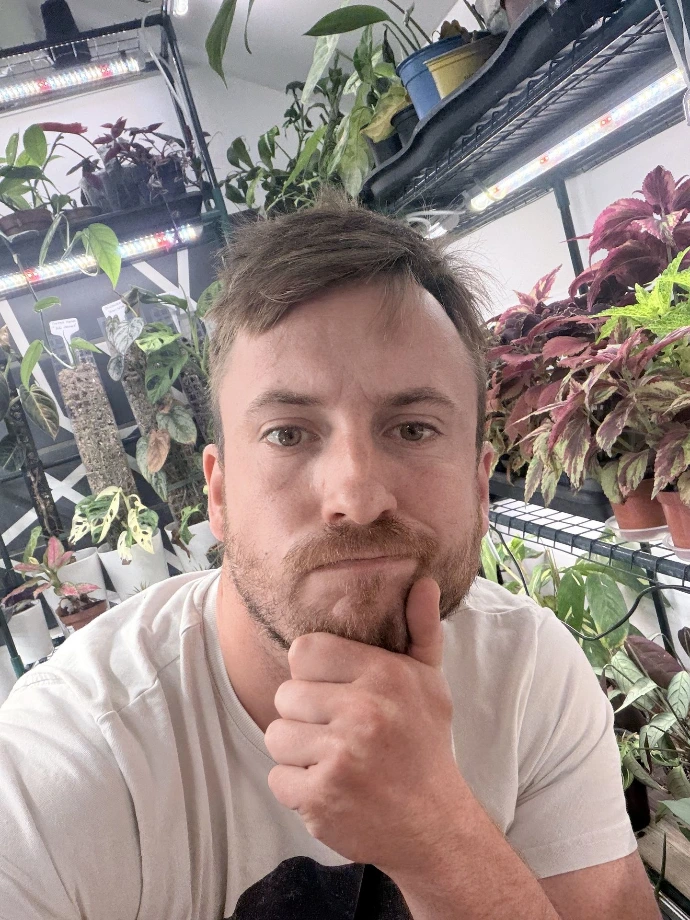 Arnaud, fondateur d'Un Jour Une Plante, dans sa pièce de culture entourée de plantes exotiques